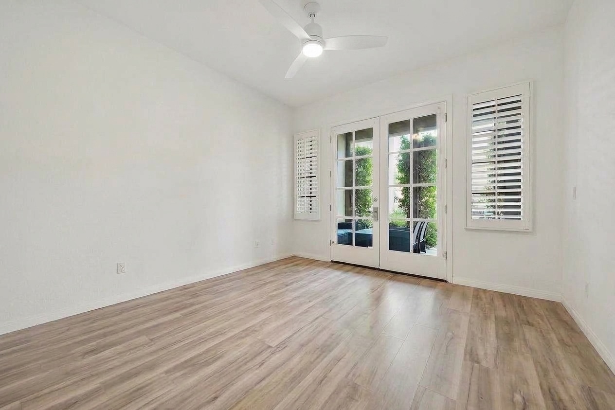 Empty room with wood floors and French doors, before virtual staging